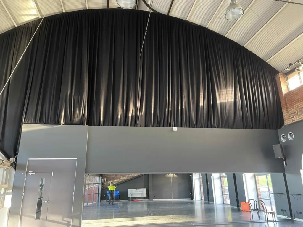 Black theatrical drapes at full fullness in a Brent Street studio