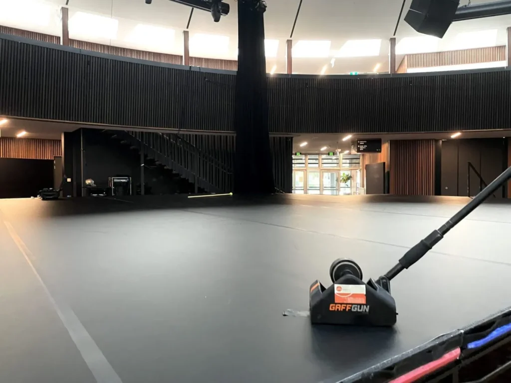 GaffGun tape applicator with STM GGm8 adapter on a black stage floor