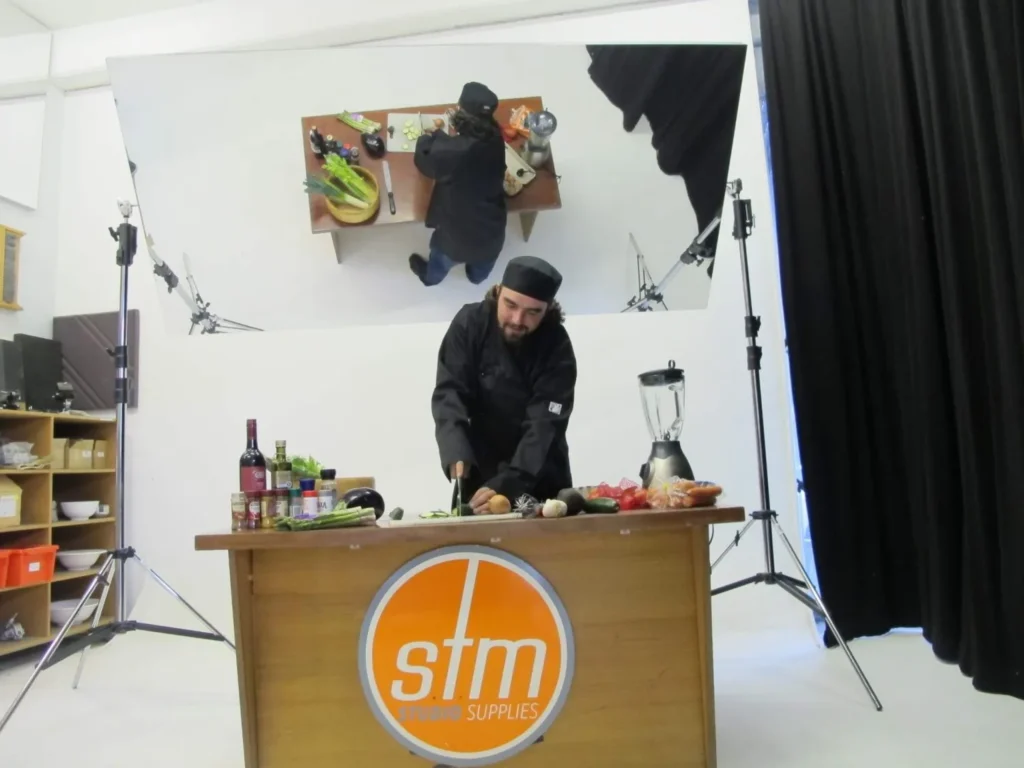 Chef at a cooking demonstration bench under an overhead Mylar demonstration mirror
