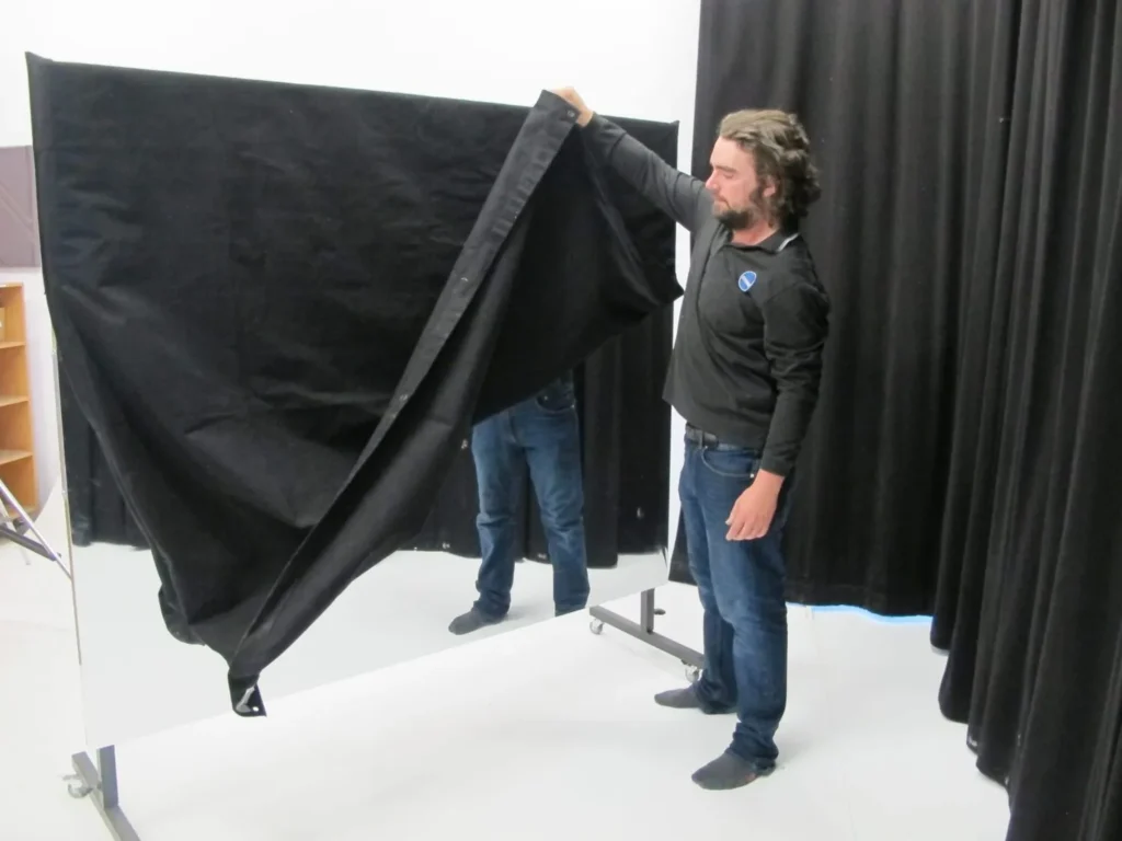 STM staff member fitting a black Molton cover over a rollaway Mylar mirror